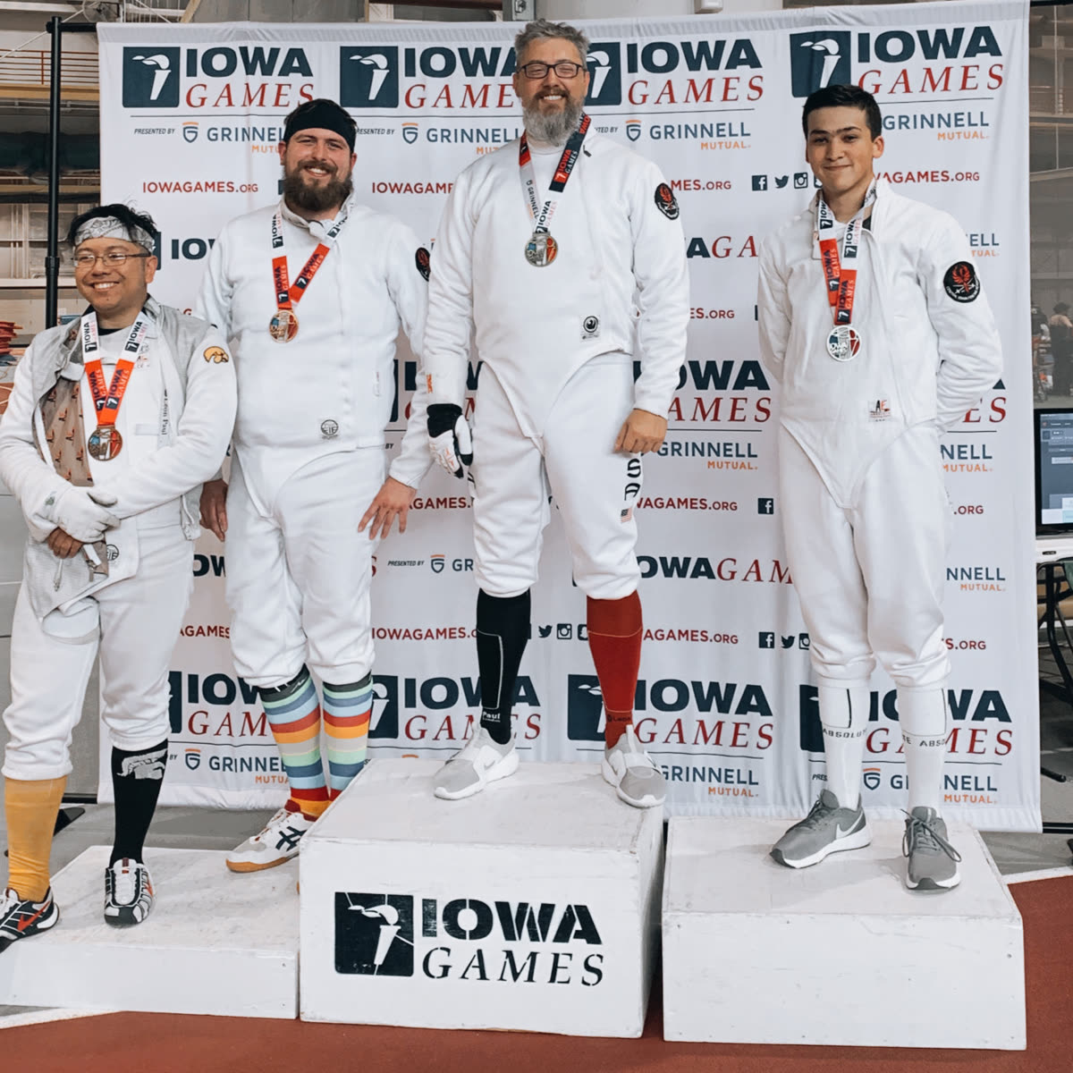Eric Rhea atop the Iowa Games podium with the fencing gold medal, 2023