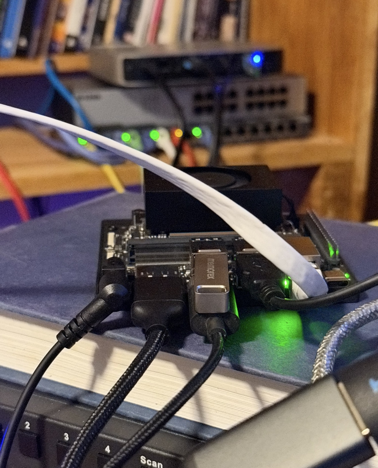 A Jetson Nano board connected with power, USB, and Ethernet cables in a small home hardware lab setup.